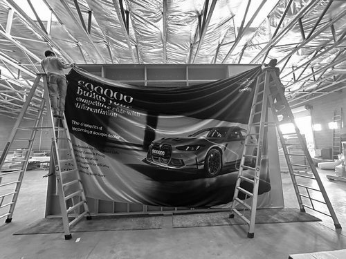 Crew tensioning a printed automotive graphic on an aluminum frame