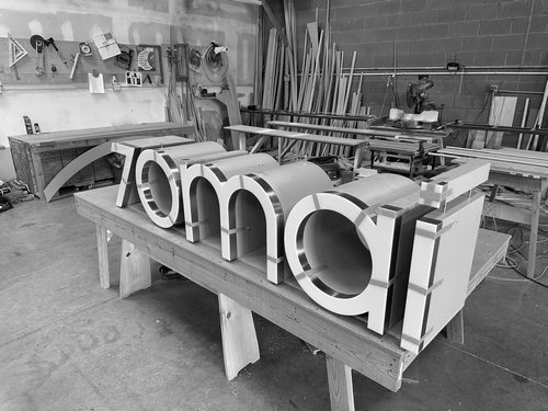 Dimensional brand letters prepared on a workshop table