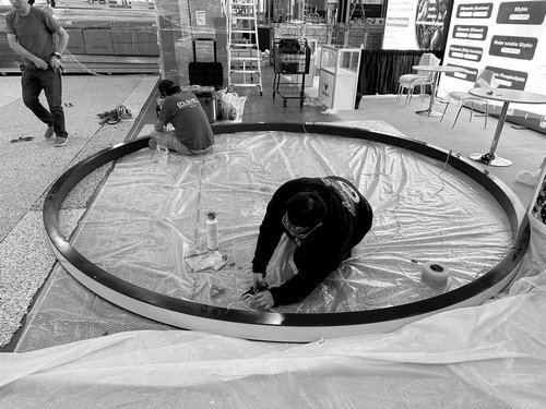 Crew assembling a circular H&M USA hanging sign on the show floor