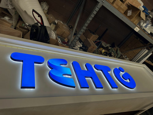 Blue illuminated dimensional letters being assembled