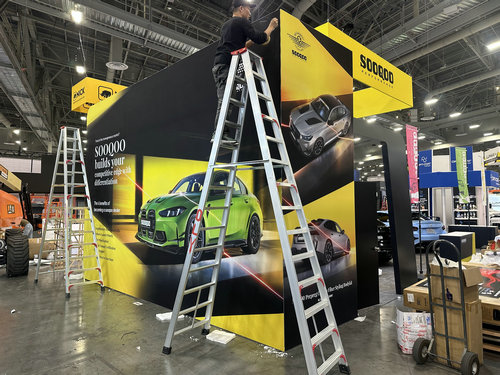 Branded exhibit wall graphics being installed on the show floor