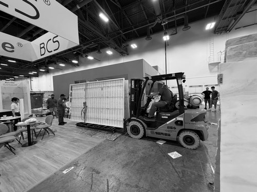 Forklift moving a large display wall on the show floor