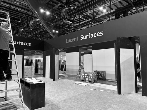 Trade show booth crew completing fit and finish under a black exhibit fascia