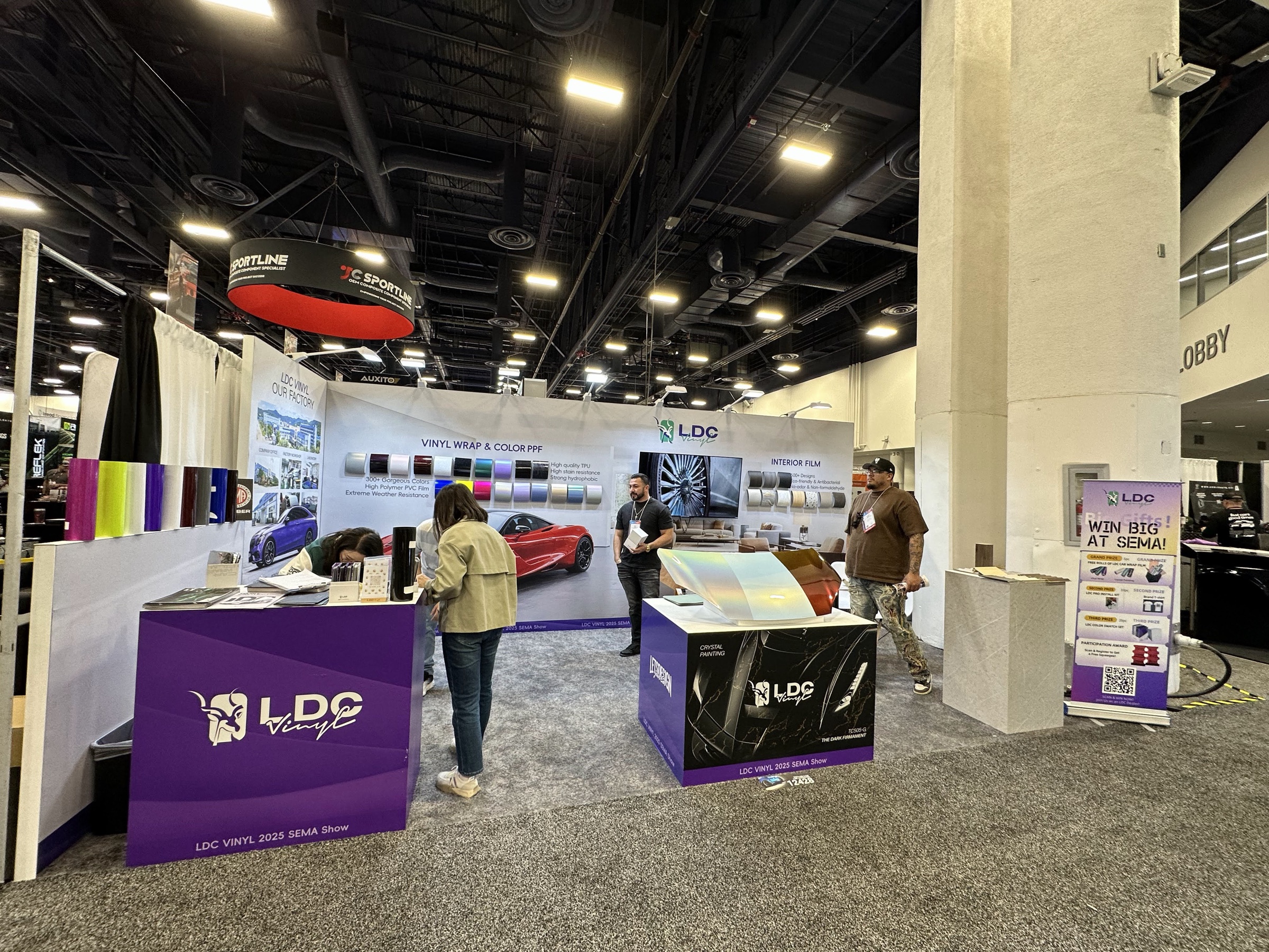 Visitors comparing LDC Vinyl wrap samples at the SEMA booth in Las Vegas